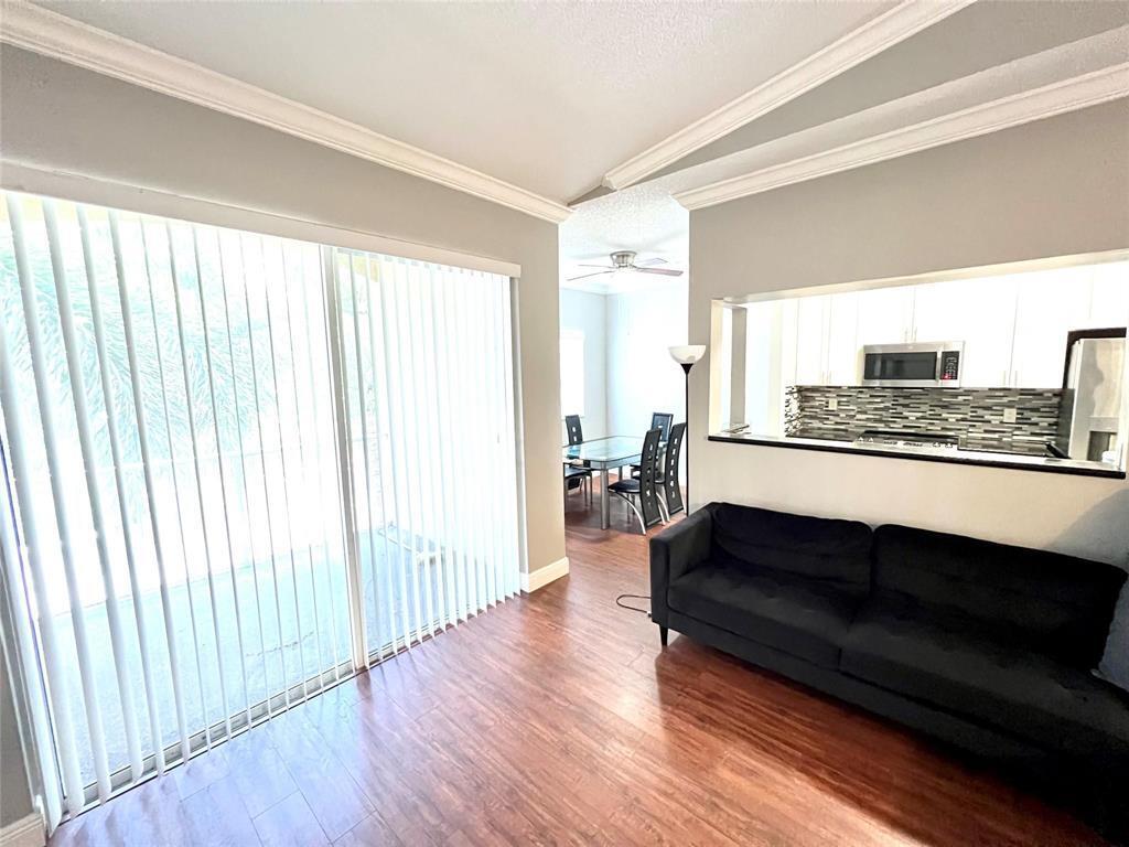A living room with wood-look flooring, a black sofa, and a view into the kitchen — 7085 Nova Drive # 226, Davie FL 33317, DAVIE, FL