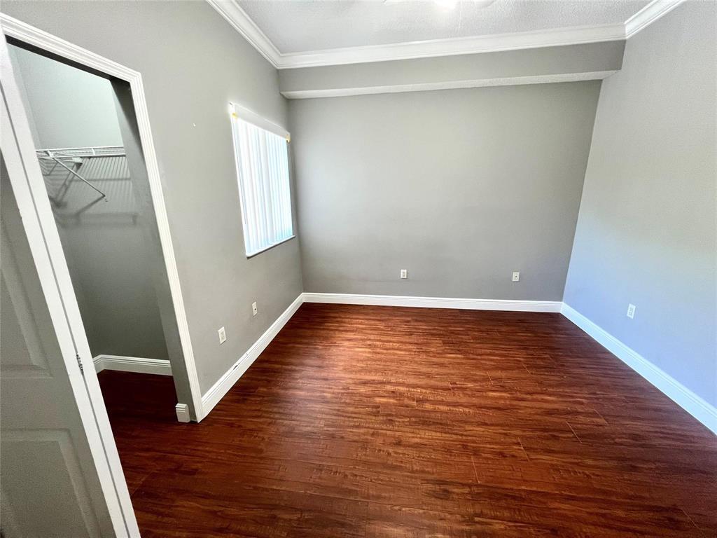 An empty bedroom features gray walls, dark wood-look flooring, a window, and a walk-in closet — 7085 Nova Drive # 226, Davie FL 33317, DAVIE, FL