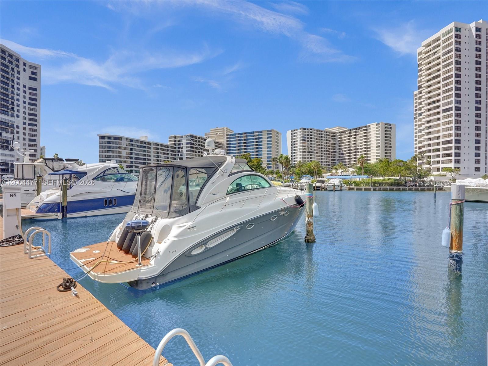 A white and gray motorboat is docked at a wooden pier near tall residential buildings — 2667 S Parkview Dr, Hallandale Beach FL 33009, HALLANDALE BEACH, FL