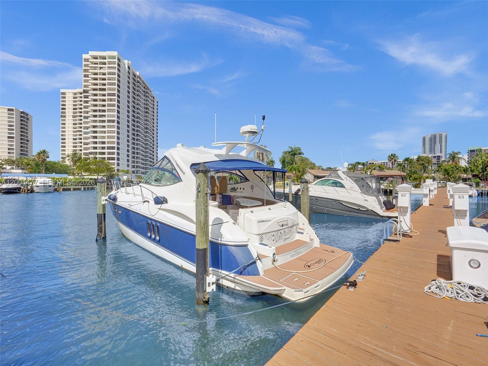 A white and blue motor yacht is docked at a wooden pier near high-rise buildings — 2667 S Parkview Dr, Hallandale Beach FL 33009, HALLANDALE BEACH, FL