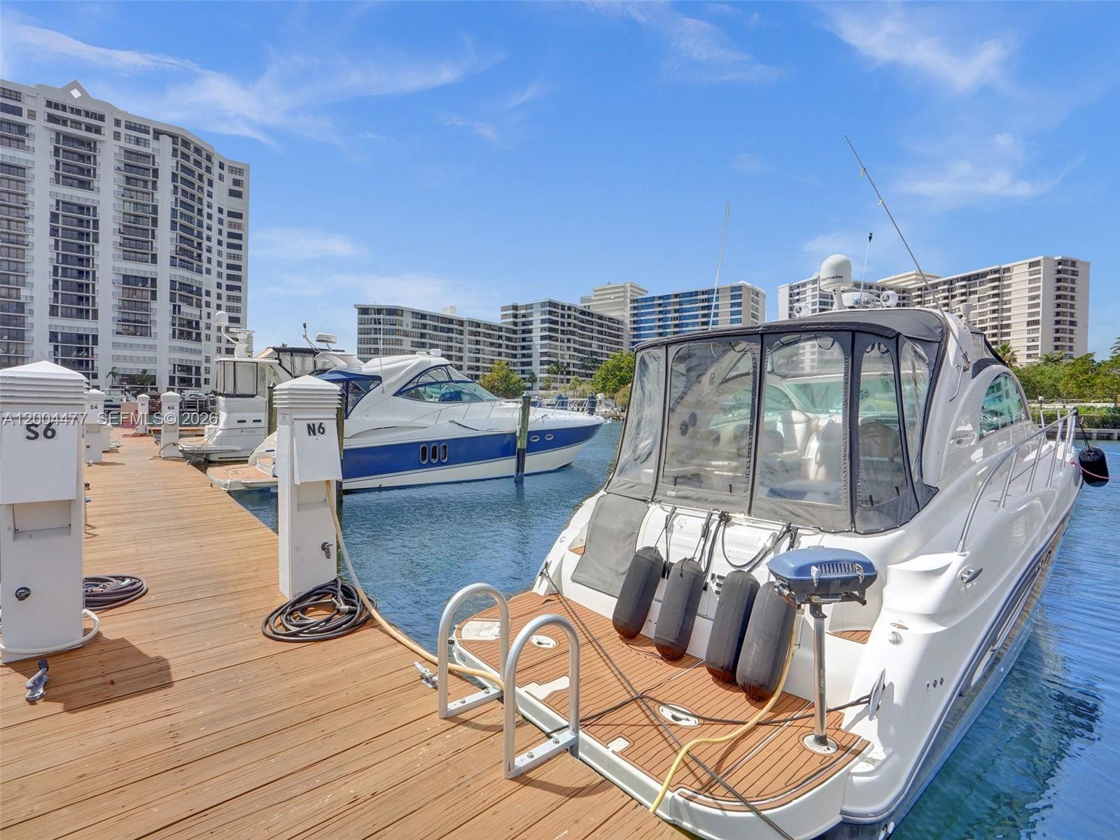 A white yacht is docked at a wooden pier in a marina with apartment buildings nearby — 2667 S Parkview Dr, Hallandale Beach FL 33009, HALLANDALE BEACH, FL