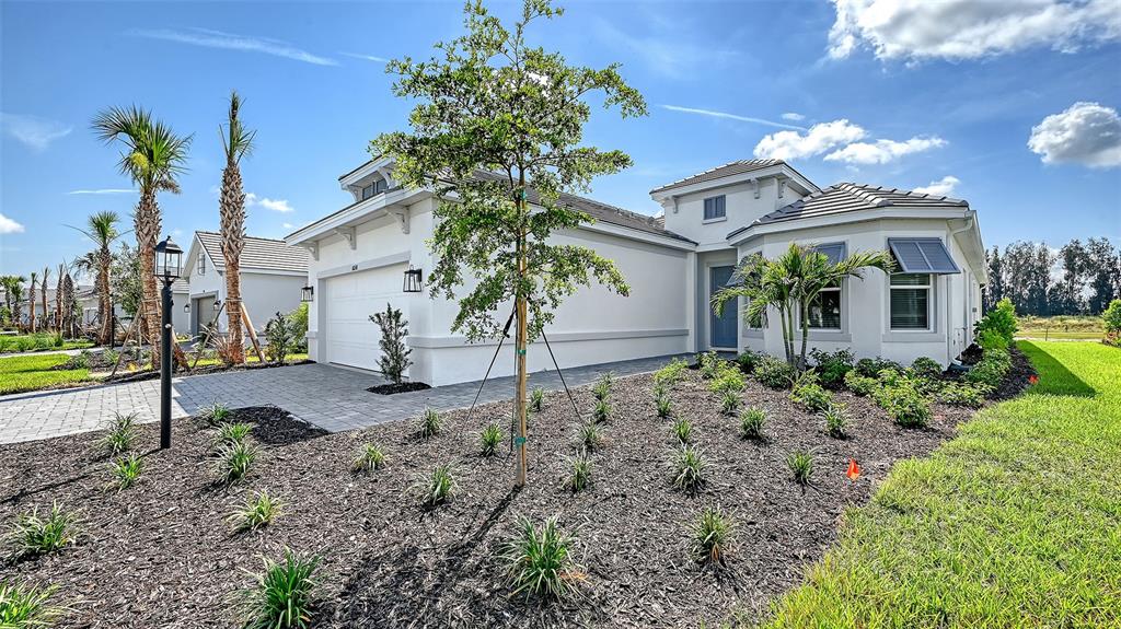 A single-story house with a white exterior, a paved driveway, and a landscaped front yard — 10248 SILENT NIGHT LANE, SARASOTA, FL