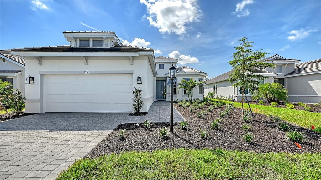A single-story house with a white stucco exterior, a two-car garage, and a paved driveway — 10248 SILENT NIGHT LANE, SARASOTA, FL