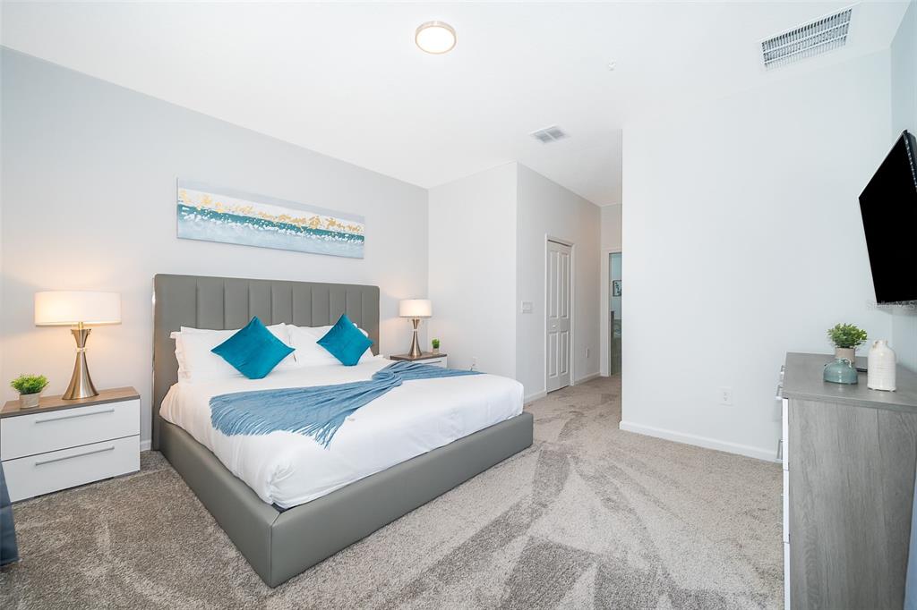 A bedroom features a gray upholstered bed, two nightstands with lamps, and gray carpeting — 8861 CABOT CLIFFS DRIVE UNIT 104, DAVENPORT, FL