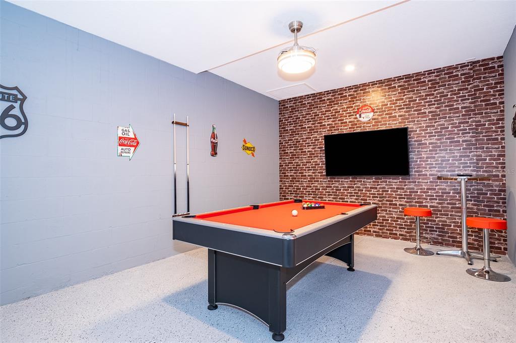 A game room features a pool table, brick accent wall, and gray block walls — 8861 CABOT CLIFFS DRIVE UNIT 104, DAVENPORT, FL