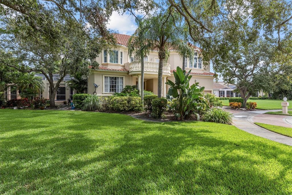 A two-story house with a red tile roof, balcony, and lush landscaping in the front yard — 5914 LA ROSA LANE, APOLLO BEACH, FL