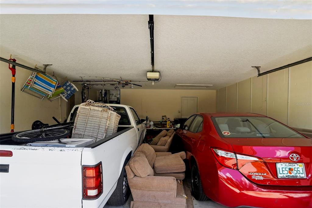 A garage contains a white pickup truck, a red sedan, and two tan armchairs — 11226 PRIMROSE CIRCLE, BRADENTON, FL