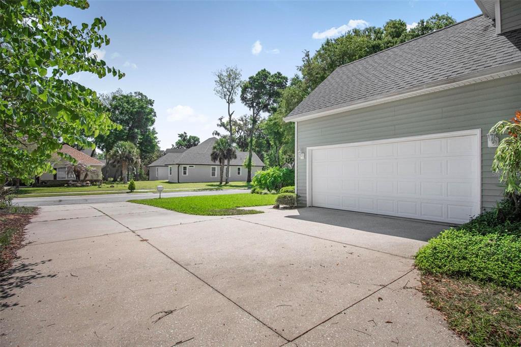 A concrete driveway leads to a two-car garage attached to a light-colored suburban home — 9 WHITEHALL COURT, FLAGLER BEACH, FL