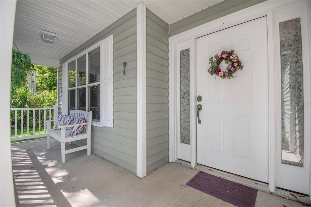 A covered front porch features light green siding, a white bench, and a white door — 9 WHITEHALL COURT, FLAGLER BEACH, FL