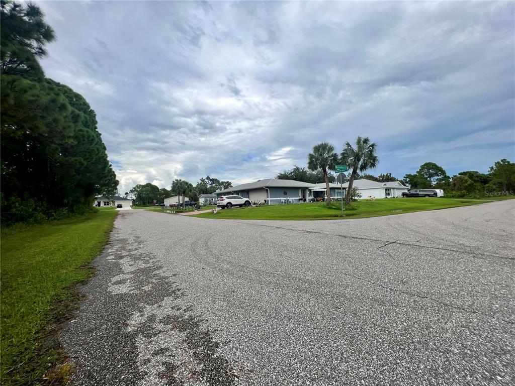 A view of a residential street corner with houses, palm trees, and a cloudy sky — 5299 HOFFMAN STREET, PORT CHARLOTTE, FL