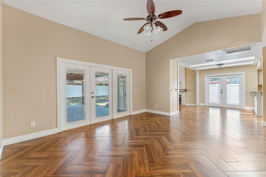 An empty room with herringbone wood-look tile flooring, a vaulted ceiling, and glass double doors — 521 LAKESHORE CIRCLE, LAKE MARY, FL