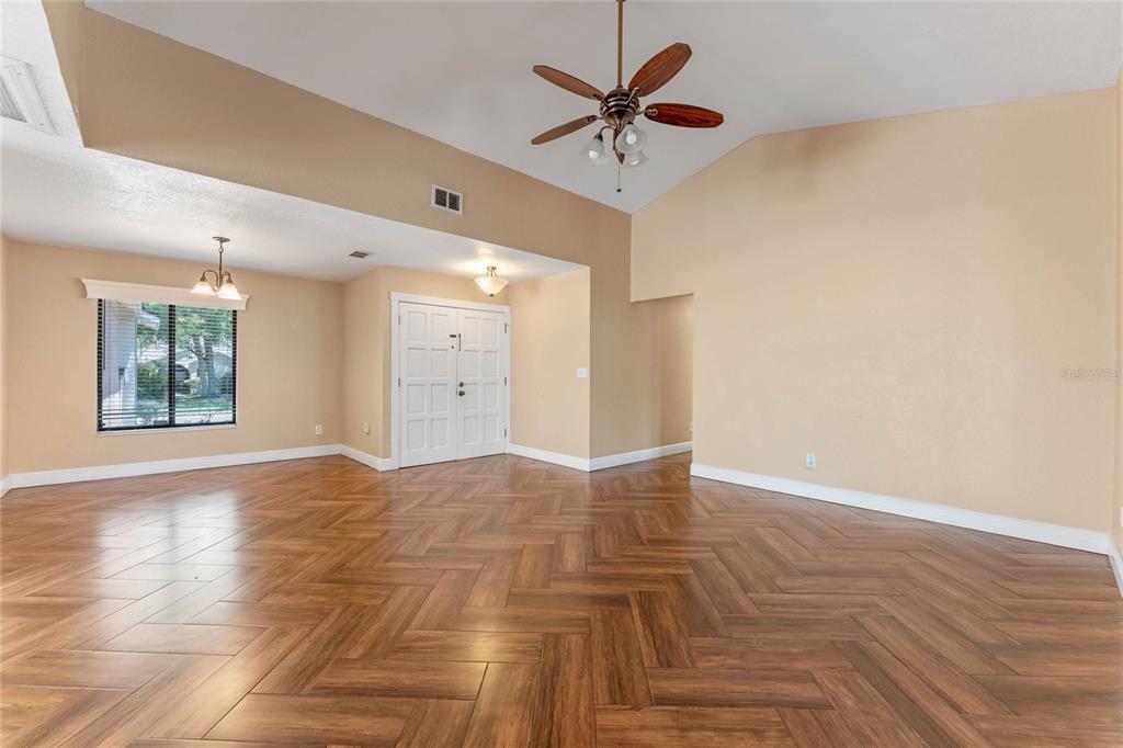 A spacious room features light-colored walls, a vaulted ceiling, and wood-look herringbone tile flooring — 521 LAKESHORE CIRCLE, LAKE MARY, FL