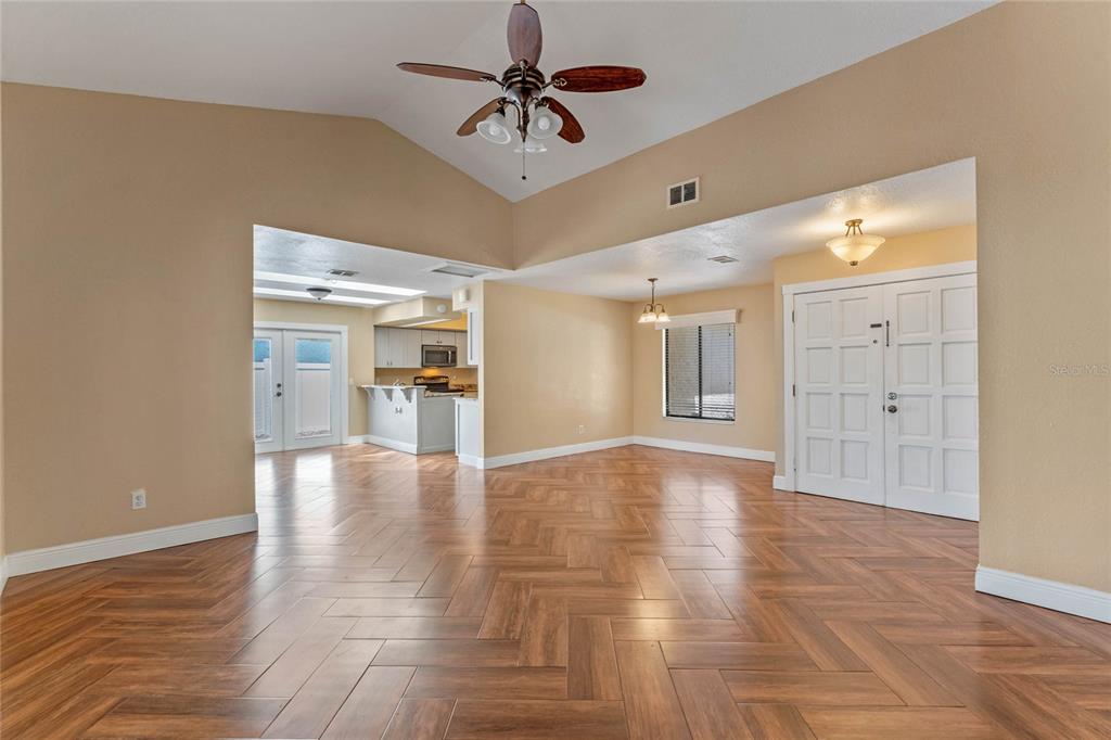 An open-concept living and dining area features herringbone wood-look flooring and a vaulted ceiling — 521 LAKESHORE CIRCLE, LAKE MARY, FL