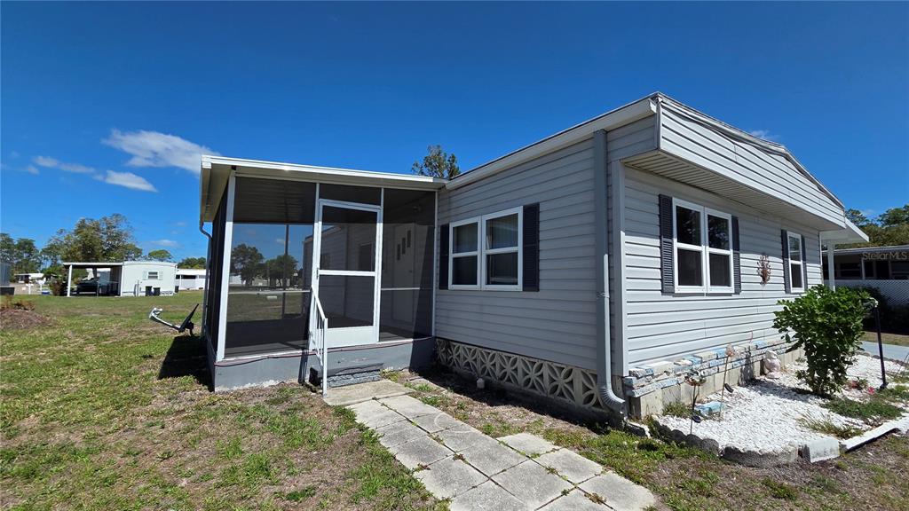 A light gray mobile home features a screened-in porch and a concrete walkway — 6881 HOLO COURT, NORTH PORT, FL