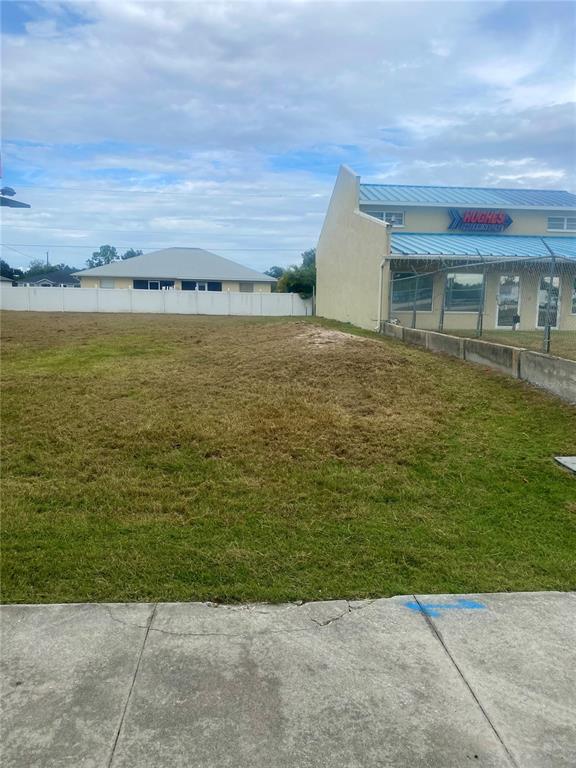 A vacant grassy lot sits next to a commercial building with a blue metal roof — 3782 N ACCESS ROAD, ENGLEWOOD, FL