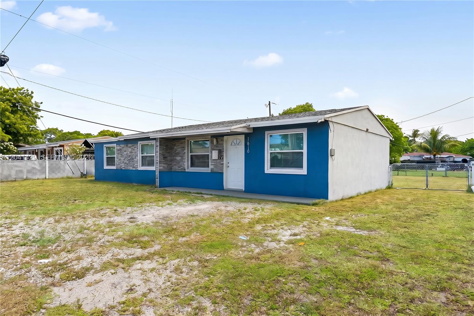 A single-story house with blue and stone-accented exterior walls sits on a grassy lot — 1610 S 22nd Ave, Hollywood FL 33020, HOLLYWOOD, FL