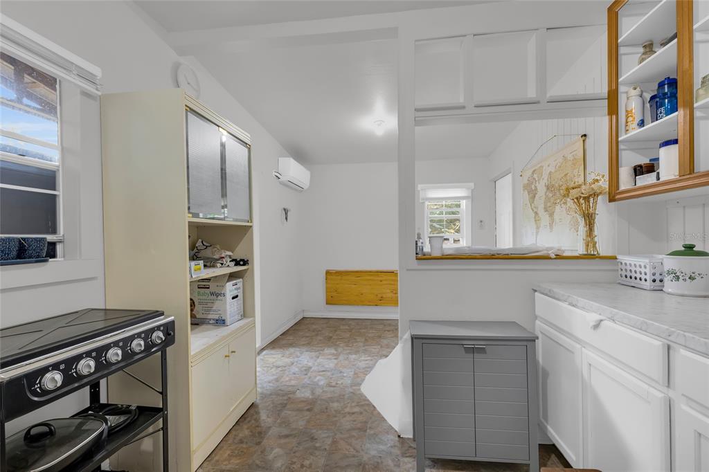 A kitchen with white cabinets, a pass-through window, and a wall-mounted folding table — 2015 NE 12TH AVENUE, OCALA, FL