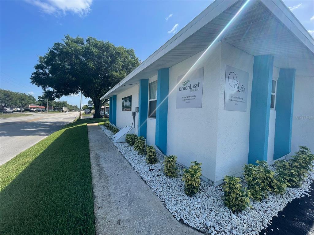 The exterior of a white commercial building features blue accents and small shrubs — 5741 9TH AVENUE N, ST PETERSBURG, FL