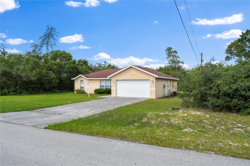 A single-story house with a tan exterior, a red roof, and a concrete driveway — 14476 SW 29TH TERRACE, OCALA, FL