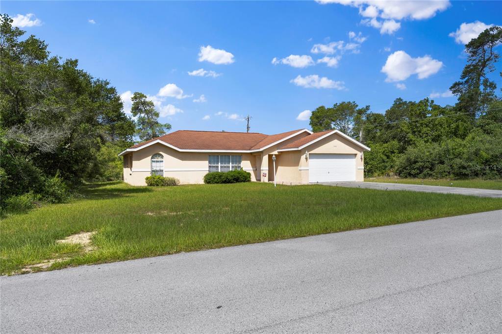 A single-story house with a tan exterior, brown roof, and attached garage sits on grass — 14476 SW 29TH TERRACE, OCALA, FL