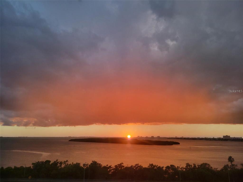 A sunset view over a body of water with a small island and distant buildings — 7100 SUNSHINE SKYWAY LANE S UNIT 906, ST PETERSBURG, FL
