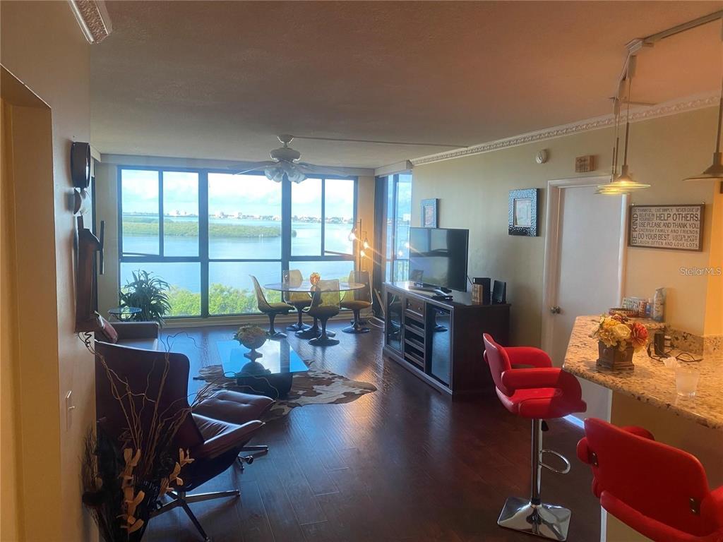 A living and dining room with hardwood floors, a water view, and red bar stools — 7100 SUNSHINE SKYWAY LANE S UNIT 906, ST PETERSBURG, FL