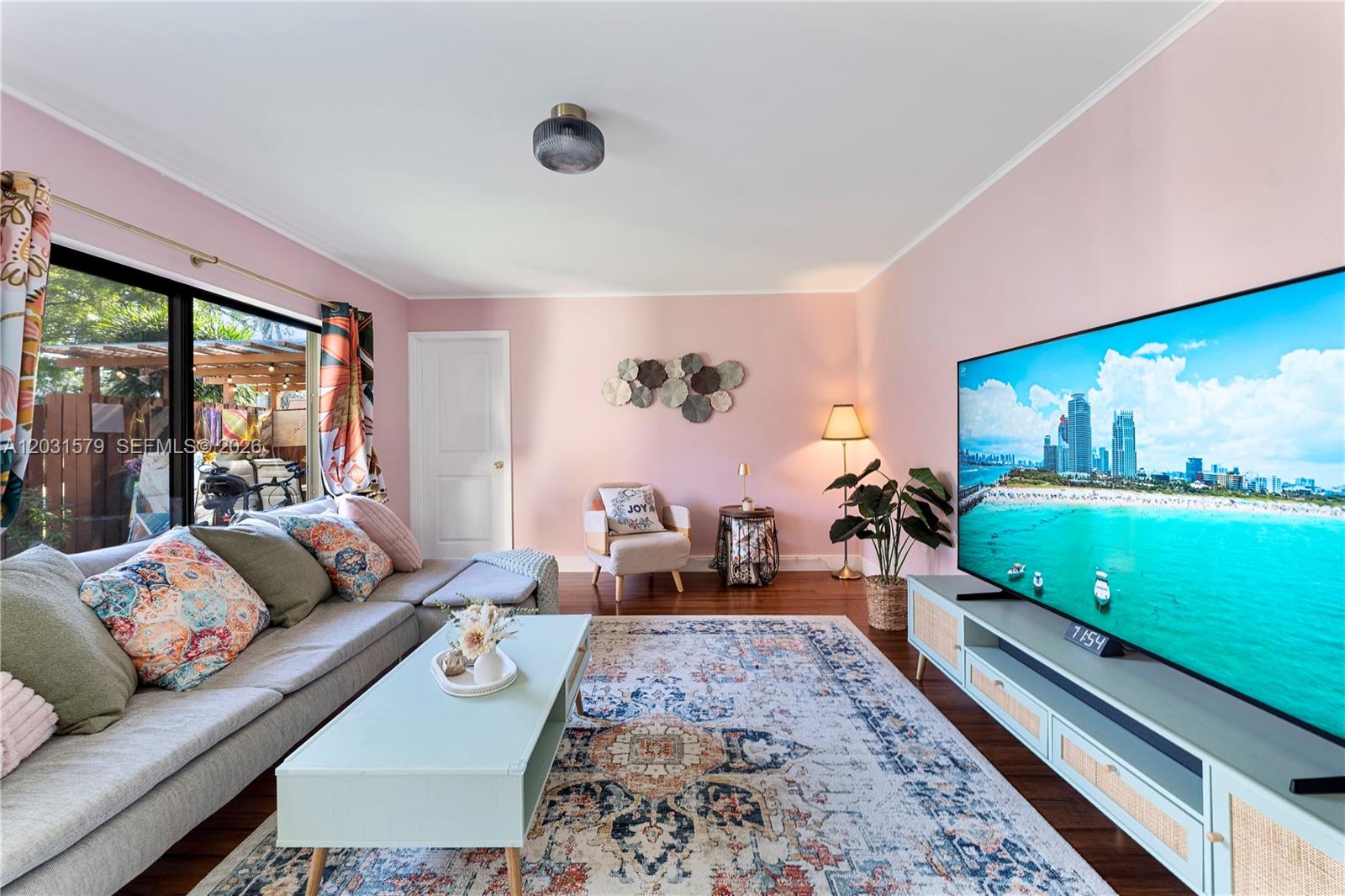 A living room features pink walls, a sectional sofa, a television, and a patterned rug — 9118c 20th ct, Davie FL 33324, DAVIE, FL
