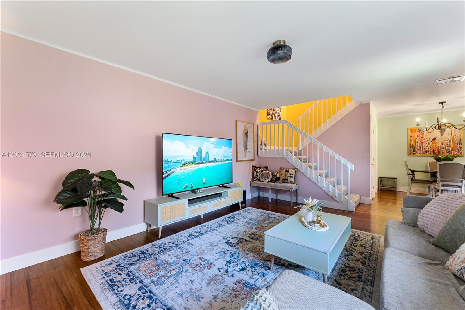 A living room features pink walls, a staircase, a television, and a patterned area rug — 9118c 20th ct, Davie FL 33324, DAVIE, FL
