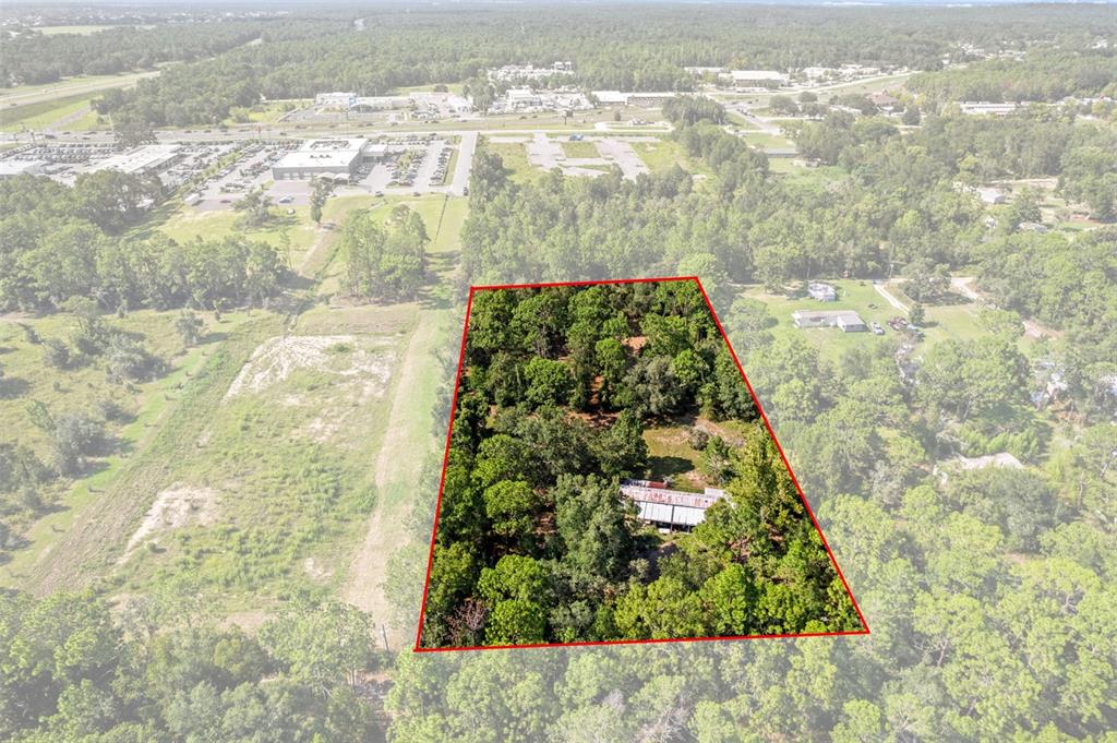 An aerial view shows a wooded lot with a small structure outlined in red — 7056 VANCE STREET, BROOKSVILLE, FL