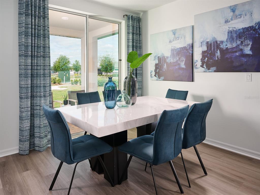 A dining room features a marble-topped table, blue upholstered chairs, and sliding glass patio doors — 857 SILVERADO TRAIL DRIVE, LAKE HAMILTON, FL