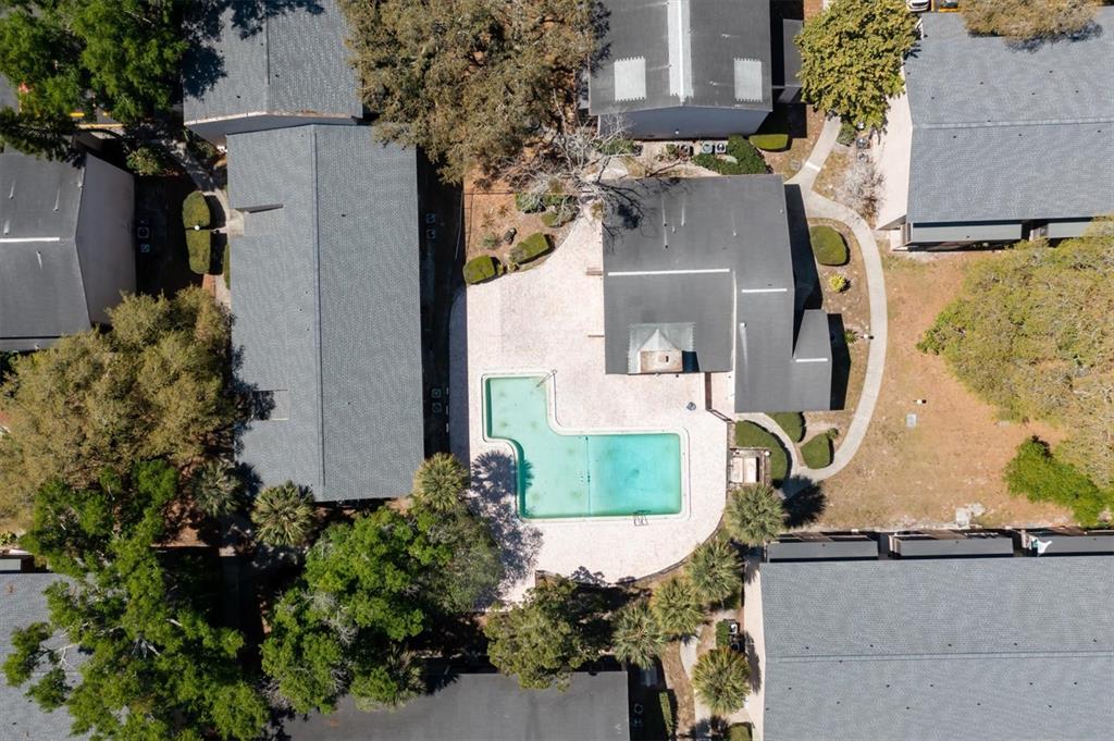 An aerial view shows an L-shaped swimming pool surrounded by a patio and apartment buildings — 7606 ABBEY LANE UNIT 208, TAMPA, FL