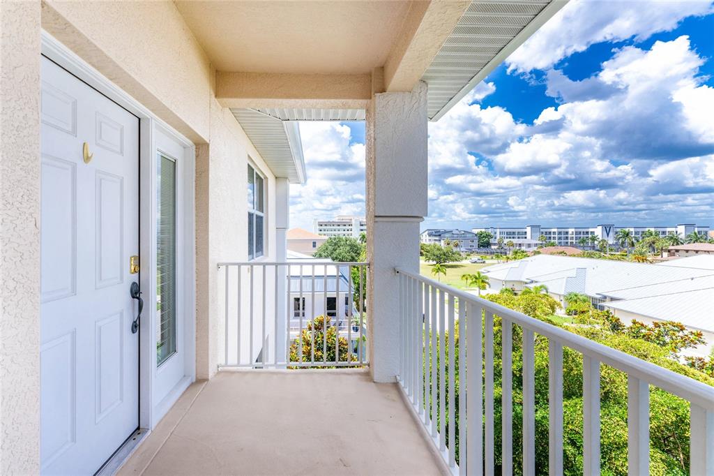 A covered balcony with a white railing overlooks a residential neighborhood under a cloudy sky — 268 LEWIS CIRCLE UNIT 143, PUNTA GORDA, FL