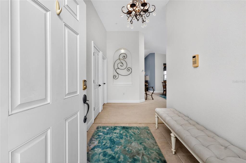 An entryway features a white door, a tufted bench, a patterned rug, and a wall niche — 268 LEWIS CIRCLE UNIT 143, PUNTA GORDA, FL