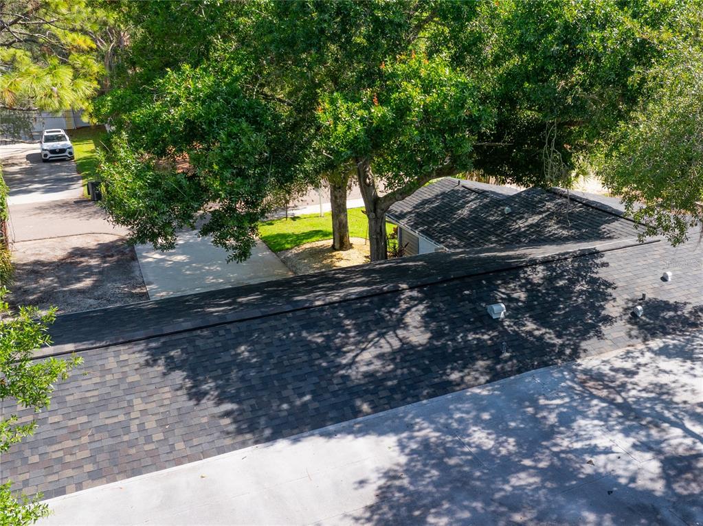 An elevated view shows a dark shingled roof, a concrete driveway, and large shade trees — 13012 96TH AVENUE, SEMINOLE, FL