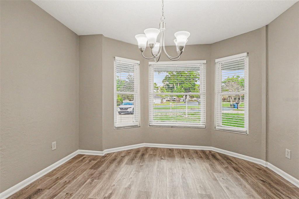 An empty dining area features light wood-look flooring, beige walls, and a bay window — 4643 VALLEY VIEW DRIVE W, LAKELAND, FL