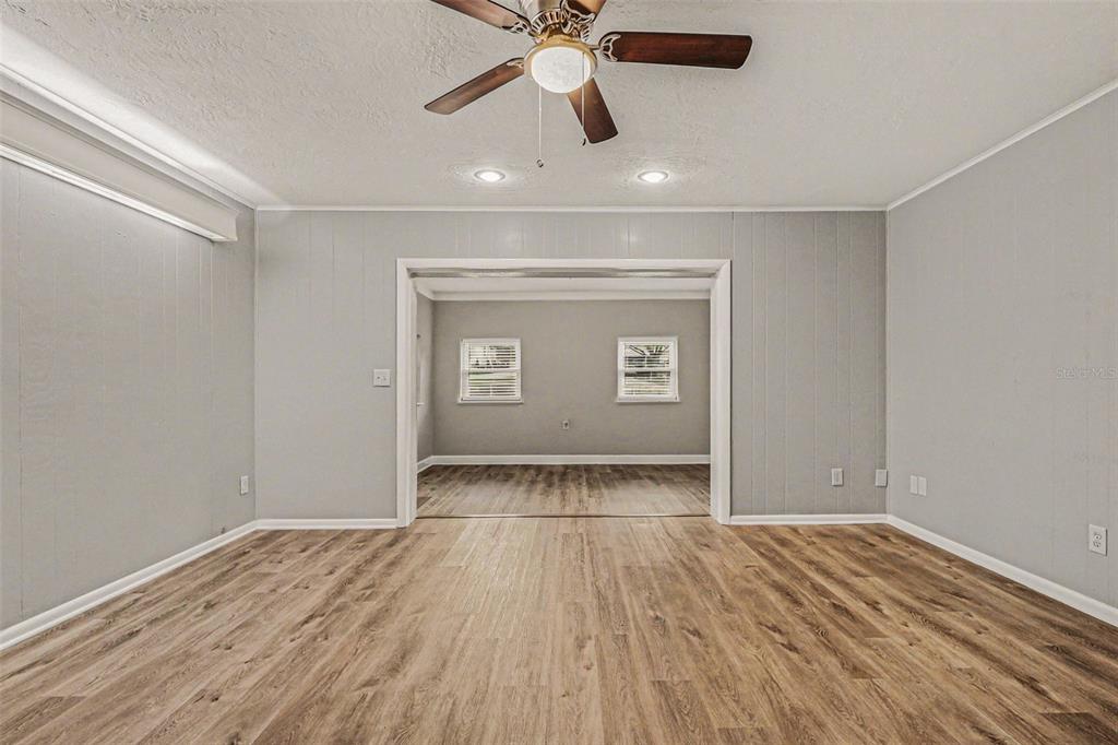 A living room with gray paneled walls, wood-look flooring, and a ceiling fan — 4643 VALLEY VIEW DRIVE W, LAKELAND, FL