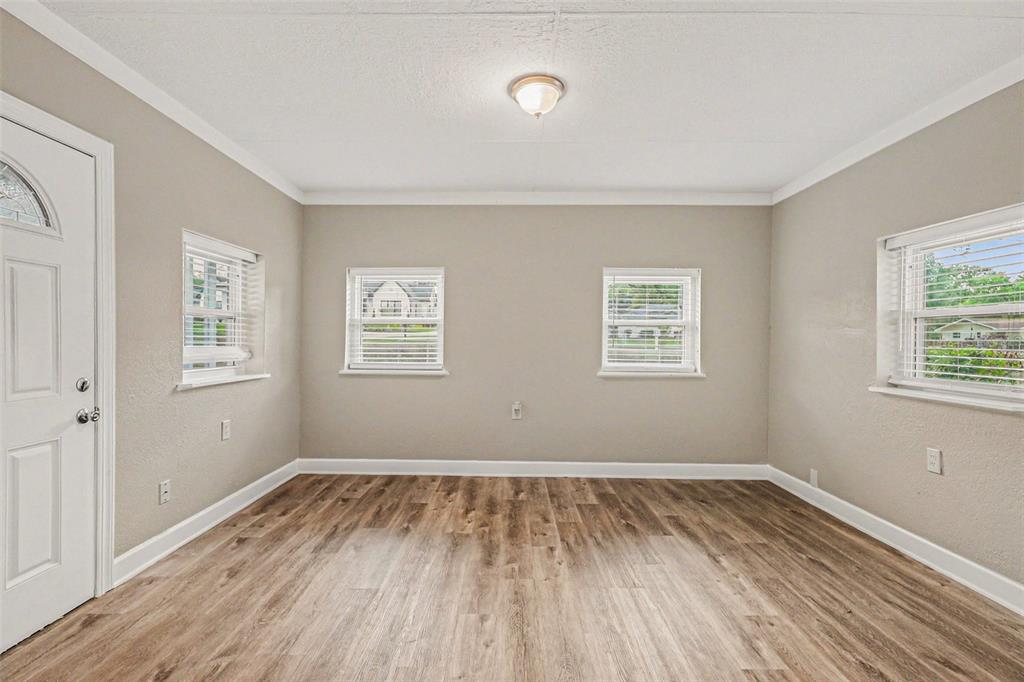 An empty room features light gray walls, wood-look flooring, and four windows with white blinds — 4643 VALLEY VIEW DRIVE W, LAKELAND, FL