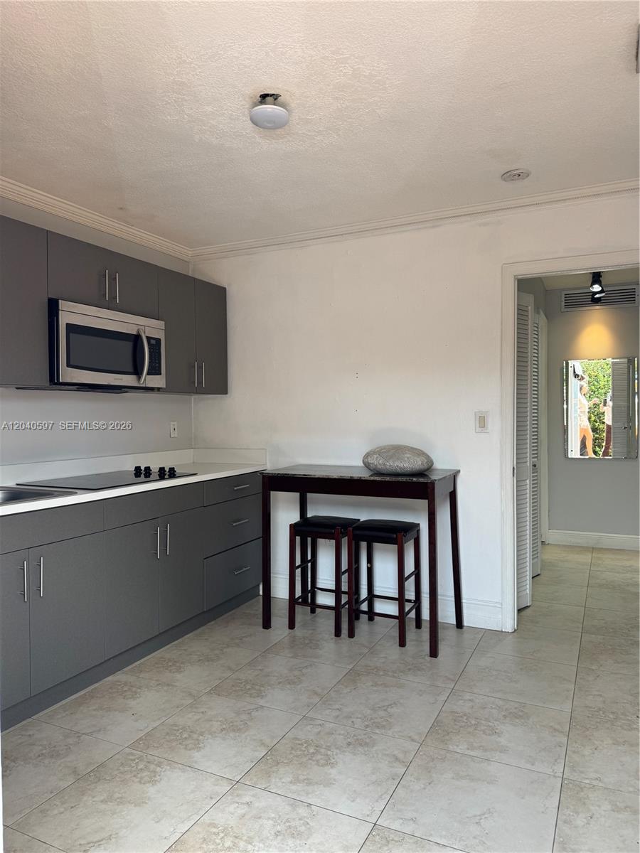 A kitchen features gray flat-panel cabinets, a built-in microwave, and a small dining table — 11340 SW 41st Ter, Miami FL 33165, MIAMI, FL