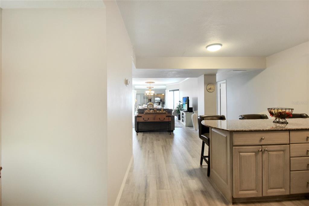 A view from a kitchen island looking toward a living room with light wood flooring — 1050 LONGBOAT CLUB ROAD UNIT 702, LONGBOAT KEY, FL