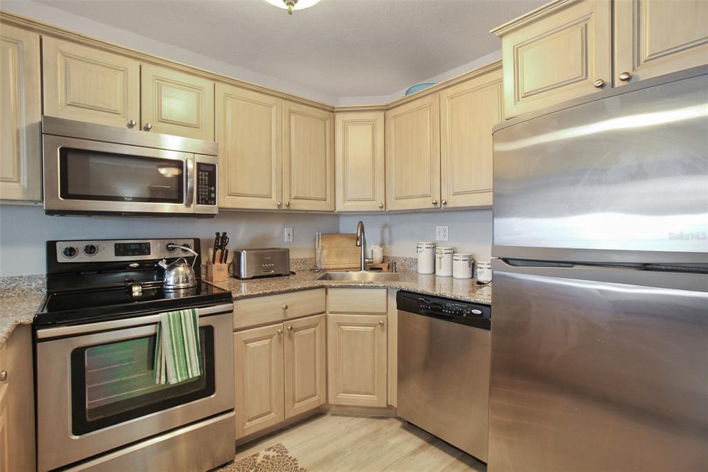 A kitchen features light wood cabinets, granite countertops, and stainless steel appliances — 1050 LONGBOAT CLUB ROAD UNIT 702, LONGBOAT KEY, FL