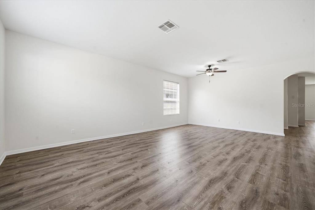 An empty room features white walls, a ceiling fan, and wood-look flooring — 13444 HAVERHILL DRIVE, SPRING HILL, FL