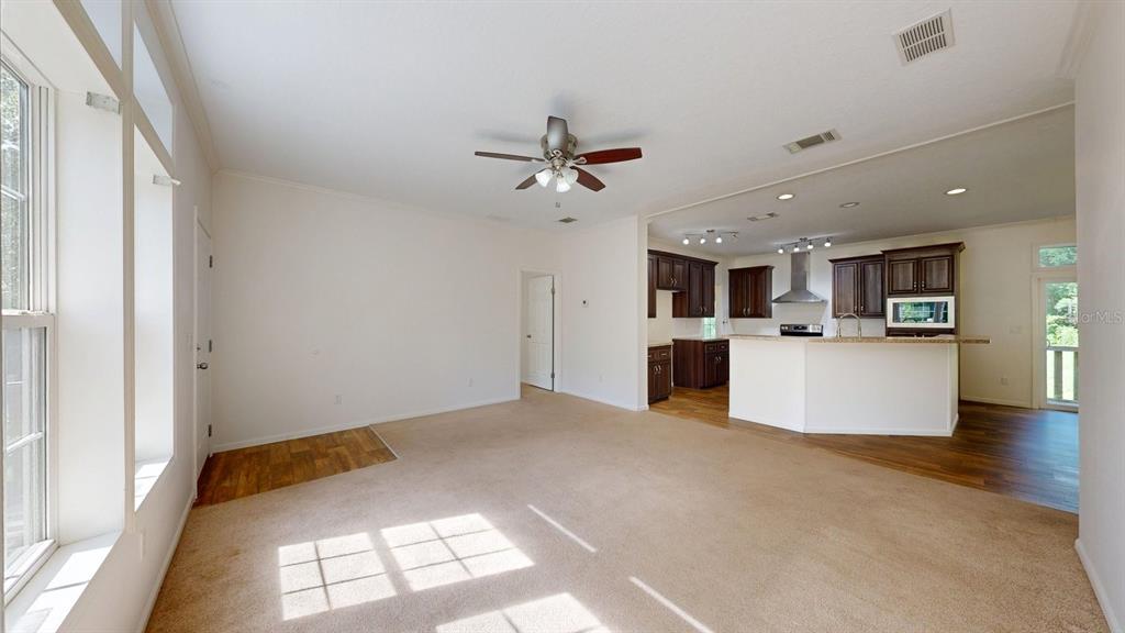 A living room with beige carpeting opens to a kitchen featuring dark wood cabinets — 2930 PALMETTO STREET, BUNNELL, FL