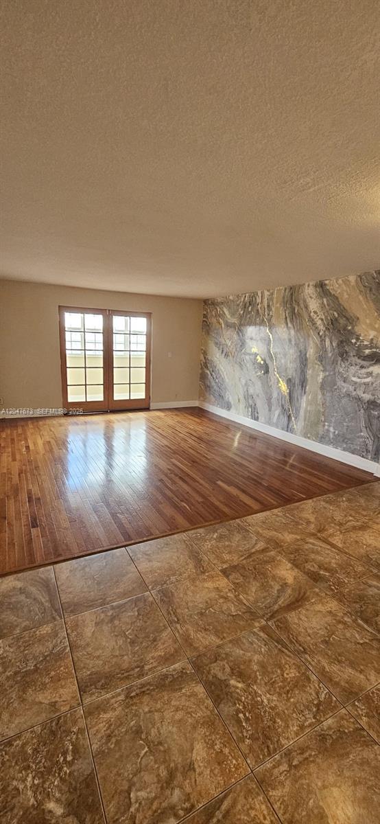 An empty room features hardwood flooring, a marble-patterned accent wall, and double glass doors — 410 NW 68th Ave # 509, Plantation FL 33317, PLANTATION, FL