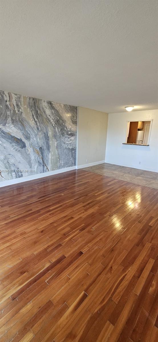 A living area features hardwood flooring, a marble-patterned accent wall, and a kitchen pass-through window — 410 NW 68th Ave # 509, Plantation FL 33317, PLANTATION, FL