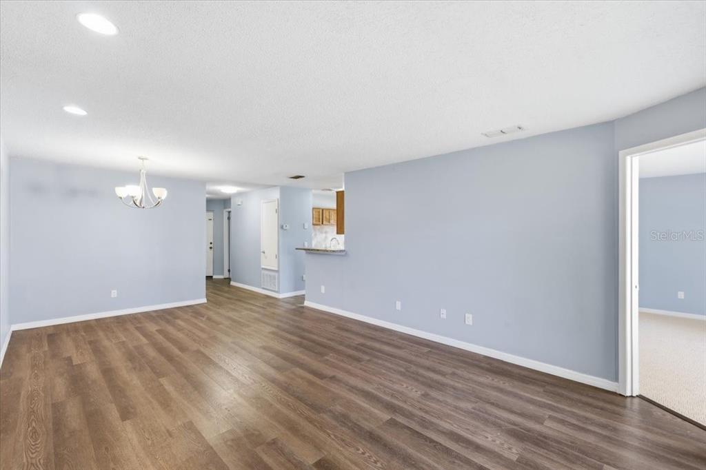 An open-concept living area features light blue walls, wood-look flooring, and a dining chandelier — 7813 SUGAR BROOK COURT UNIT 7813, ORLANDO, FL