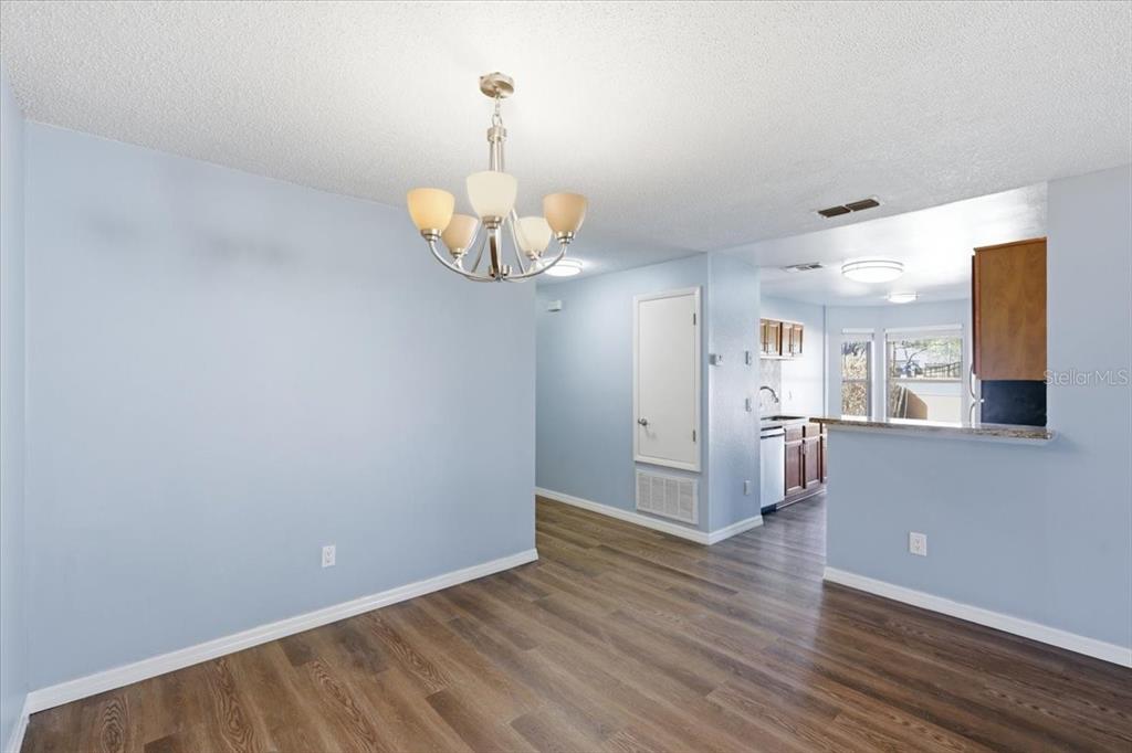 A dining area with light blue walls, wood-look flooring, and a central chandelier — 7813 SUGAR BROOK COURT UNIT 7813, ORLANDO, FL