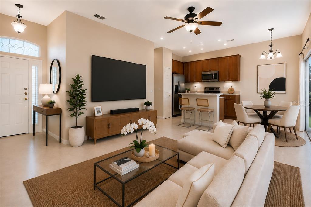 An open-concept living room and kitchen featuring a large television, sectional sofa, and dining area — 3857 WOOD THRUSH DRIVE, KISSIMMEE, FL