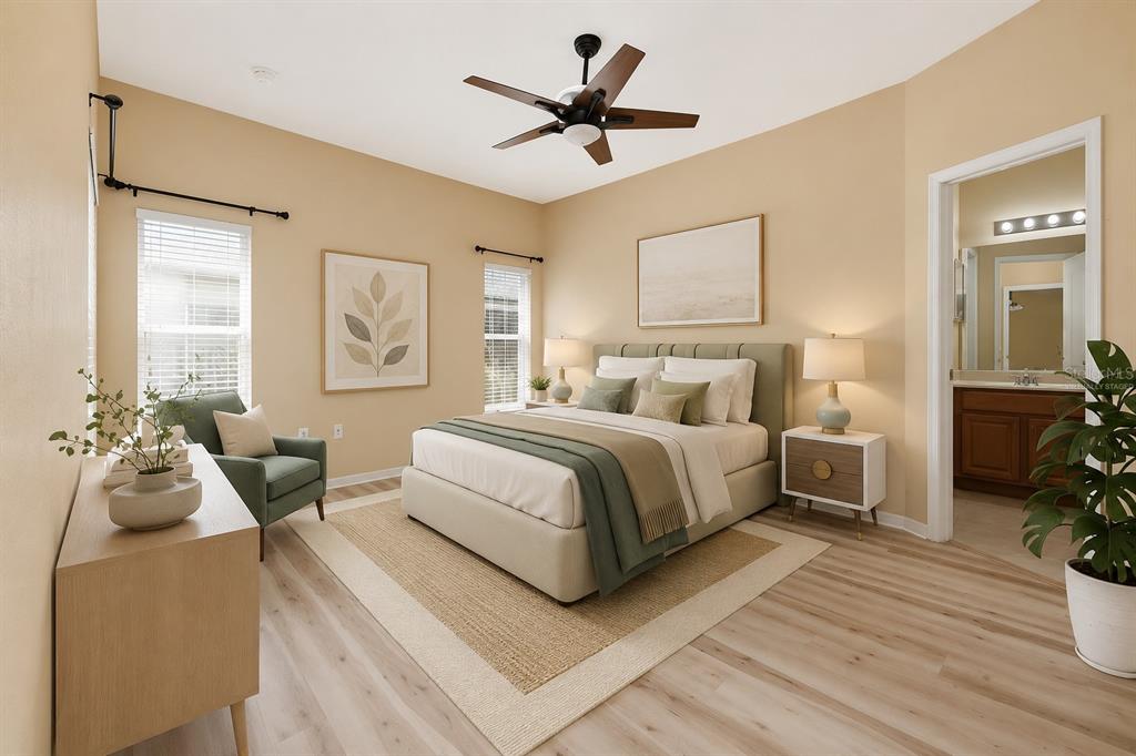 A bedroom with light wood floors, a bed, a ceiling fan, and an attached bathroom — 3857 WOOD THRUSH DRIVE, KISSIMMEE, FL