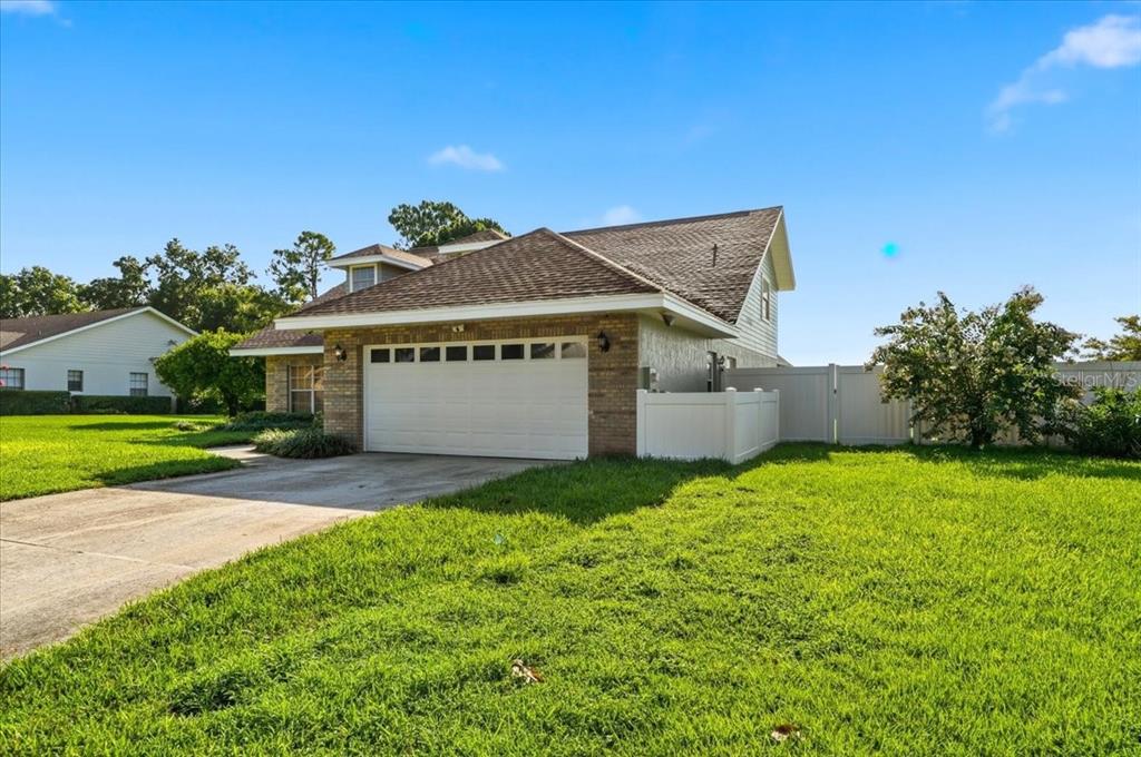 A single-story house with a brick facade, a two-car garage, and a white vinyl fence — 814 CARLTON COURT, WINTER HAVEN, FL