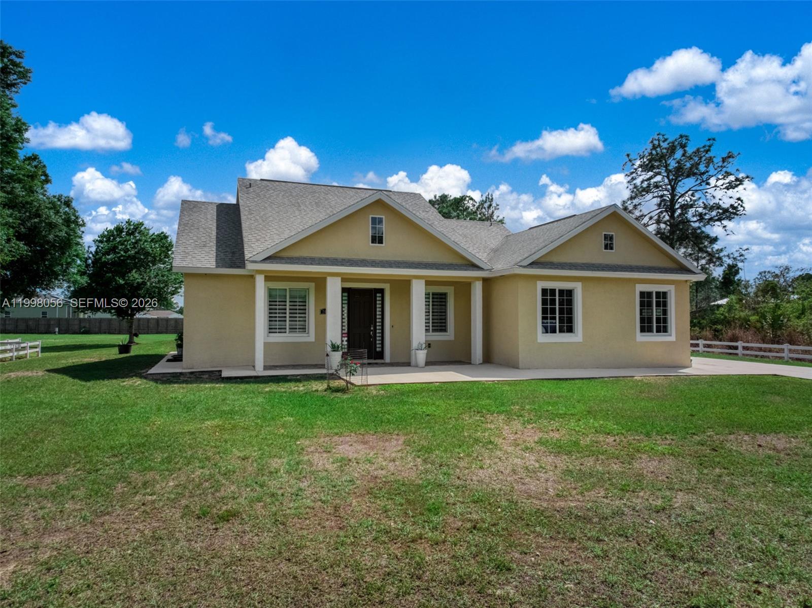 A single-story yellow house with a covered front porch sits on a grassy lawn — 2009 Flower, Sebring FL 33875, SEBRING, FL